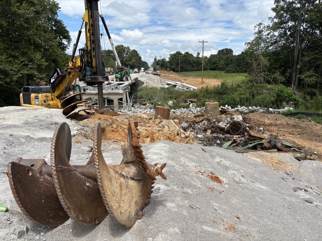 A massive augur with drilling for foundations taking place in the background.