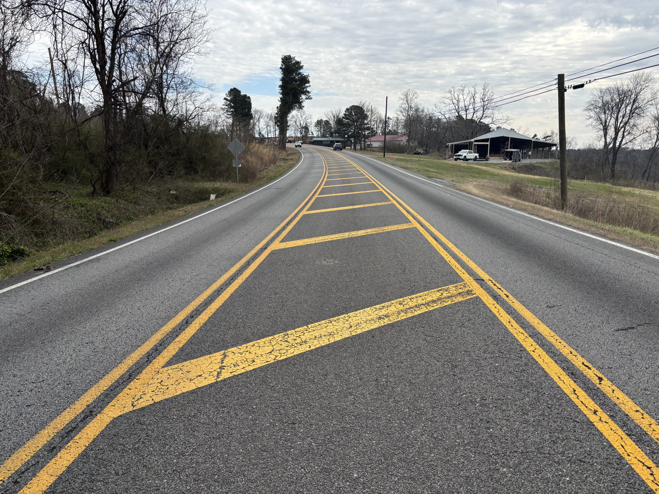 A two-lane roadway with a hatched area in the center, indicating the beginning/ending of a center turn lane.
