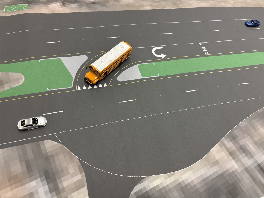 Model vehicles on a scale map demonstrate how loons — large, paved areas in the shoulder of the highway — help larger vehicles with complete U-turns.