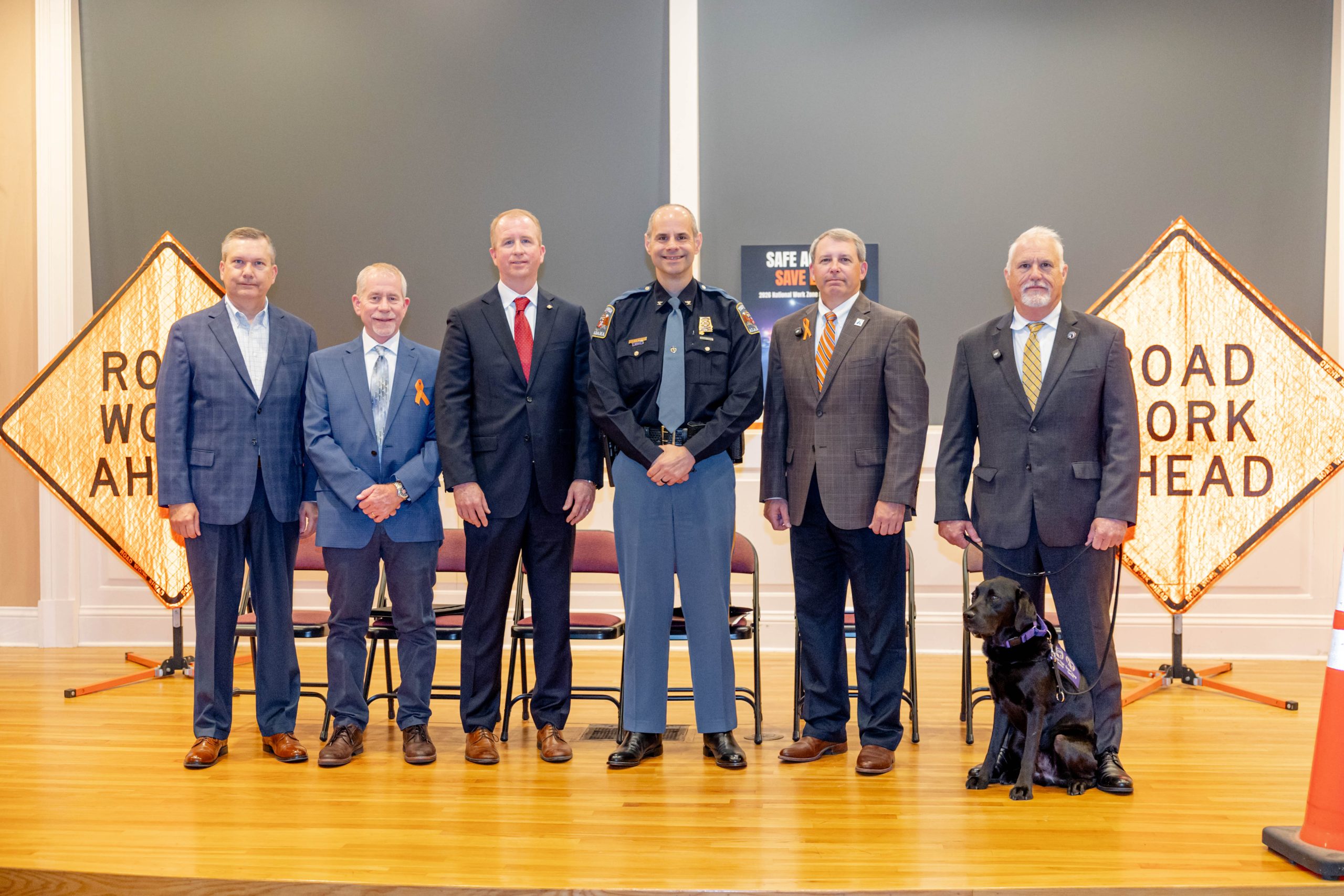 6 men standing on a stage in front of Road Work Ahead signs