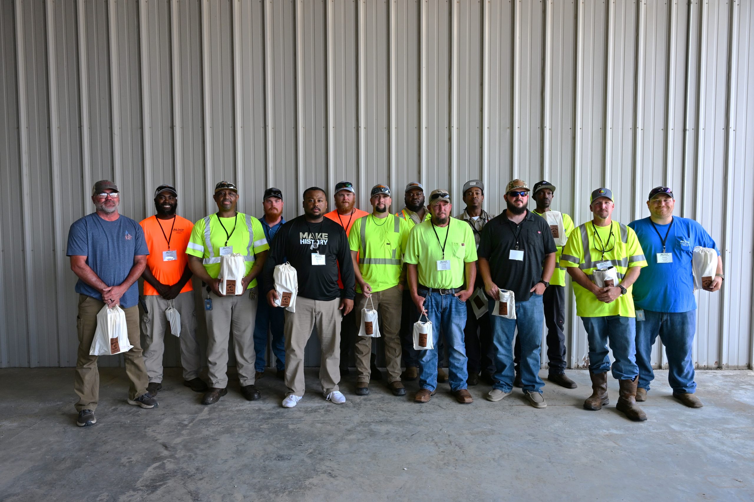 A group of ALDOT employees stand in front of a wall