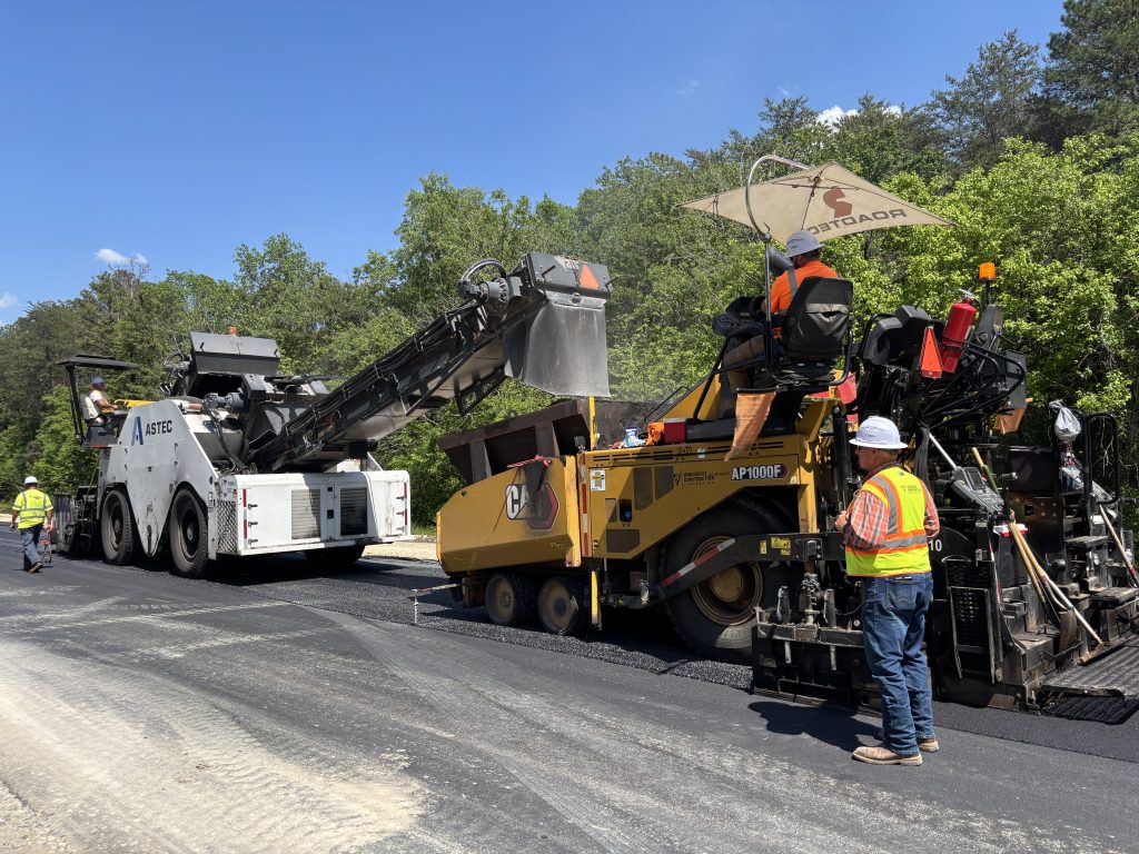 Workers paving a new roadway with a paving machine