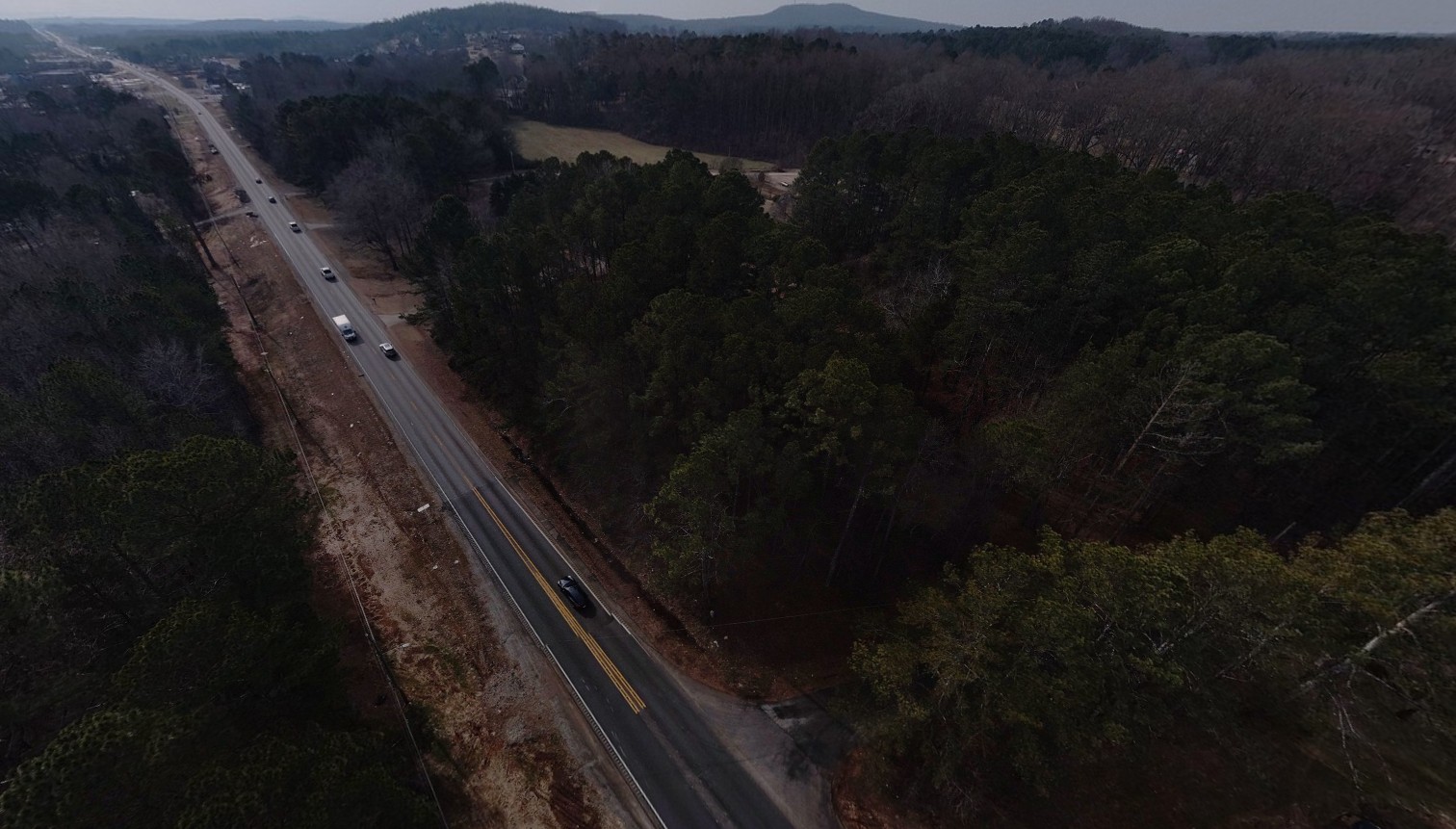 An aerial view of the project area, consisting of a two-lane road. Clearing for utility relocations is visible on the west
