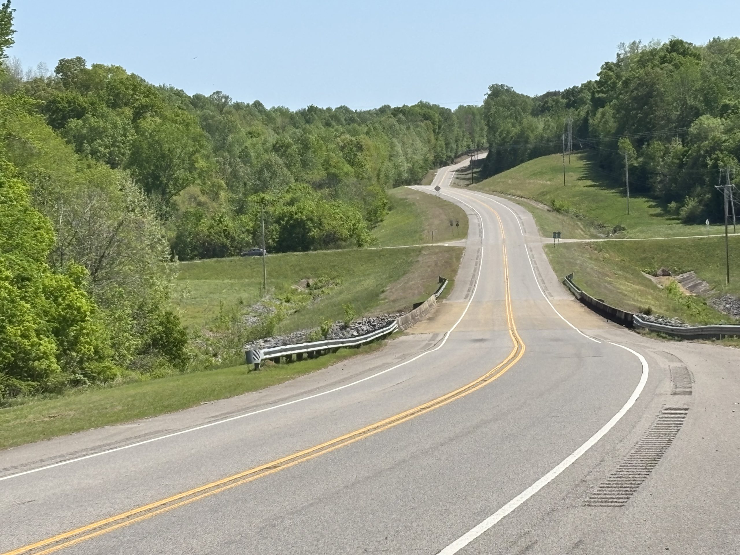 A two-lane highway winds through hilly terrain
