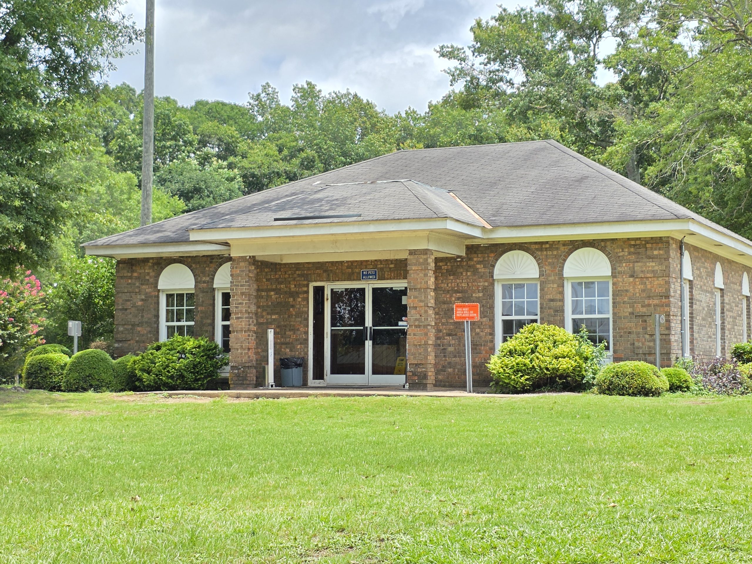 The I-65 North Rest Area in Butler County brick rest area building with a covered entryway, arched windows, and landscaping, surrounded by green lawns and trees.