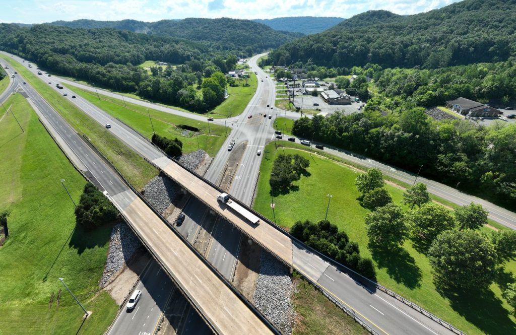 An aerial view of an interstate crossing  a four-lane highway with multiple intersections.