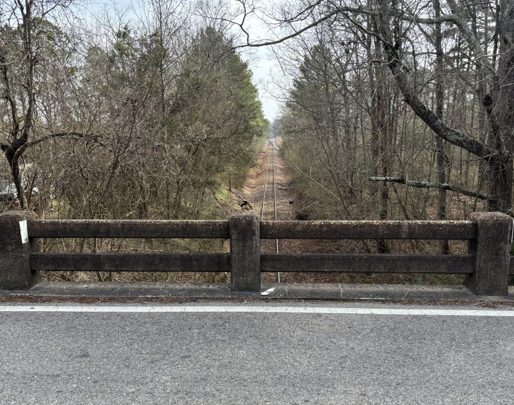 A view of railroad tracks from behind an aged bridge rail