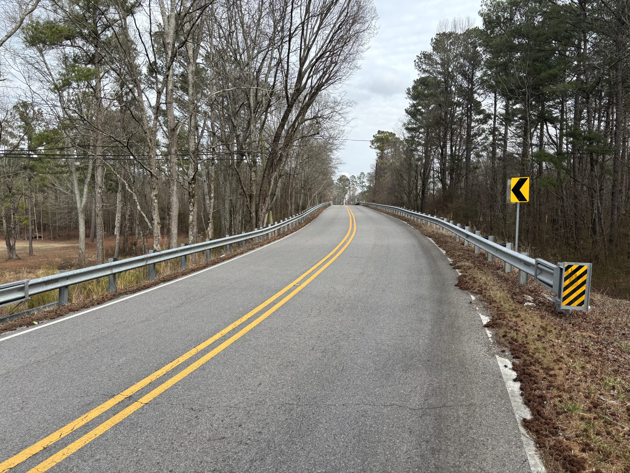 A roadway curving left and up to a bridge.