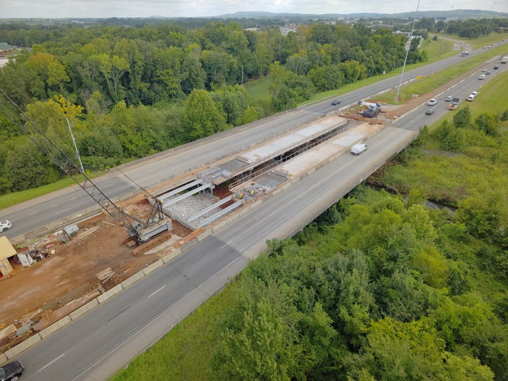 Two bridges in the process of being widened. The bridge deck is in place on all but the final spans of either bridge, where girders have just been installed.