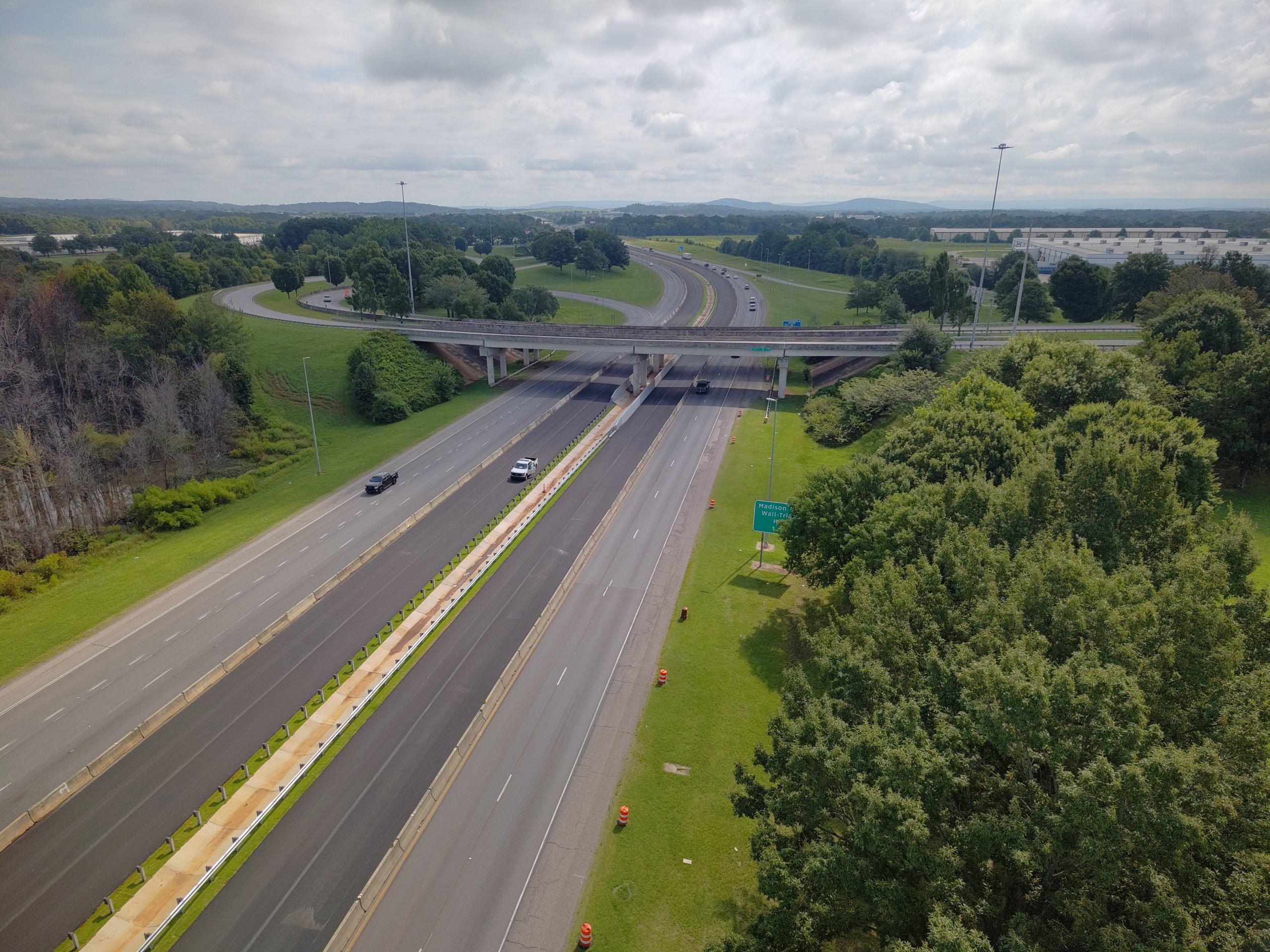 An interstate highway going under an overpass. On each side, the newly-paved inside lanes are separated from the outer two lanes by concrete barriers.