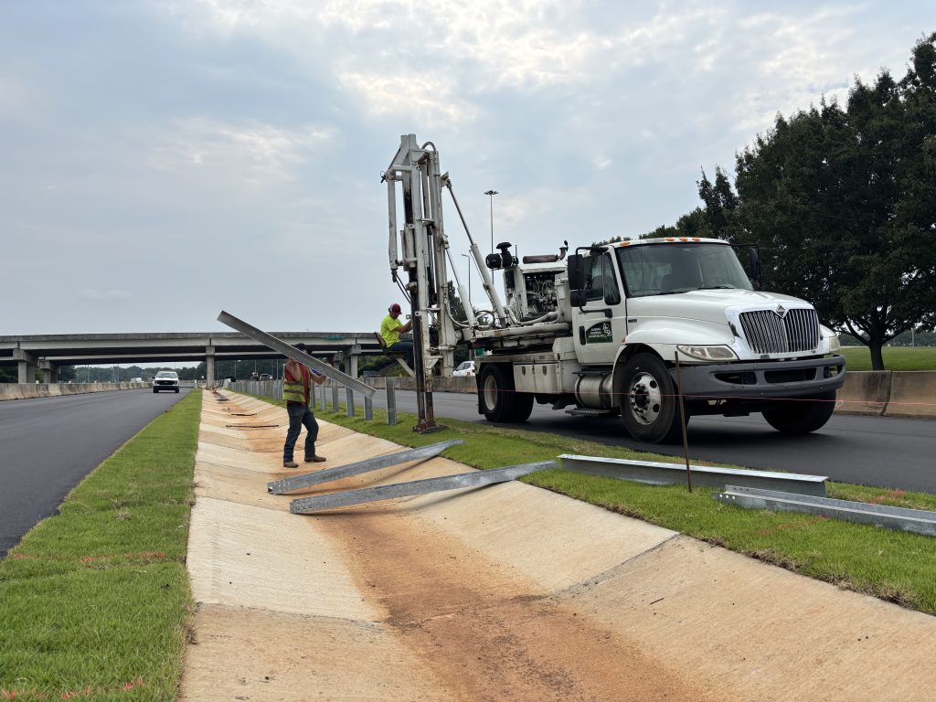 Workers install guardrail posts.
